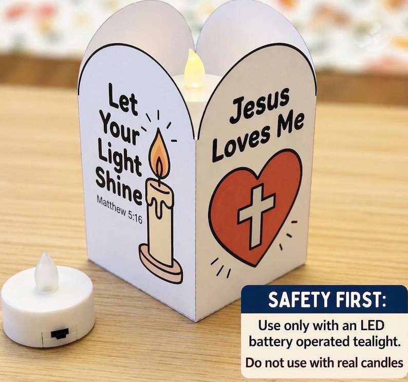 May include: A white paper lantern featuring a candle illustration with the text Let Your Light Shine Matthew 5:16 and a red heart with a cross and the text Jesus Loves Me. An LED battery operated tealight is placed next to the lantern.