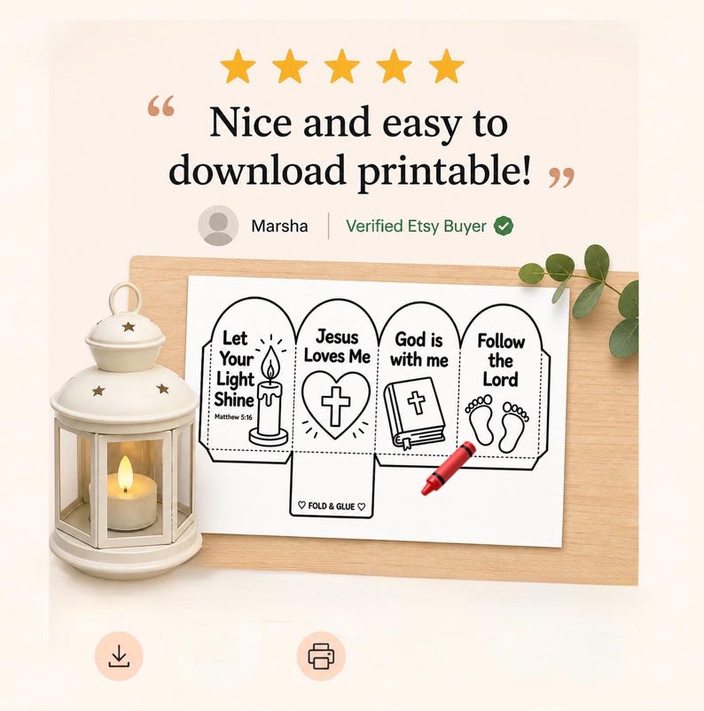 May include: A white lantern with a lit candle sits beside a printable paper craft featuring four panels with religious text and illustrations including a candle, heart with cross, bible, and footprints, with a red crayon resting on the paper.