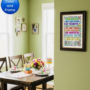 Op de afbeelding: Een ingelijste print met de tekst "FAMILY RULES" in kleurrijke letters hangt aan een groene muur. De print zit in een donkerbruine lijst. Een eettafel is gedekt met een bloemstuk en een verjaardagstaart.