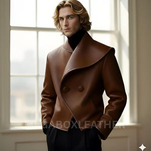 May include: A brown leather jacket with a unique collar design and two buttons. The jacket has a double-breasted style and a sleek, modern look. The text "GABOXLEATHER" is visible on the jacket.