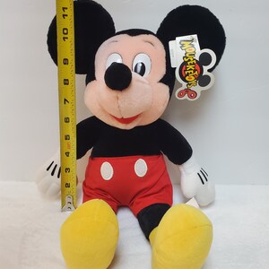 May include: A plush Mickey Mouse doll, approximately 33 cm tall, with black ears, a black body, red shorts, and yellow shoes. The doll has white gloves and a tag that reads "MOUSE-KE-TOYS".