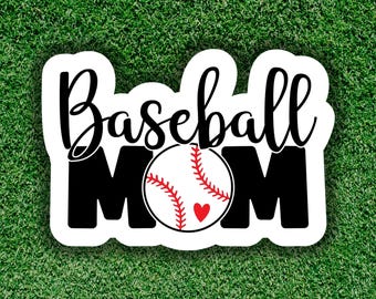 Op de afbeelding: Een witte sticker met de tekst "Baseball MOM" in zwarte script- en blokletters. Een honkbal met rode stiksels en een rood hart staat in het midden. De sticker staat op een groene achtergrond.