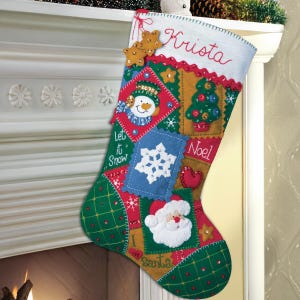 Peut inclure: Une chaussette de Noël faite à la main avec un motif patchwork. La chaussette présente un bonhomme de neige, un sapin de Noël, un flocon de neige et le Père Noël. Le nom "Krista" est brodé sur le dessus. Décorée avec des accents rouges, verts, bleus et dorés.
