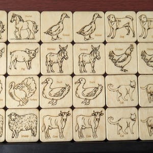 May include: Wooden animal flashcards featuring engraved illustrations of farm animals, including horses, ducks, dogs, pigs, donkeys, chickens, turkeys, cats, sheep, cows, and goats. Each card is labeled with the animal's name.