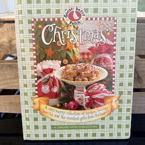 May include: A cookbook titled "Christmas Book 7" by Gooseberry Patch. The cover features a festive design with a Christmas tree, gifts, and a plate of treats. The book includes recipes and gift ideas.