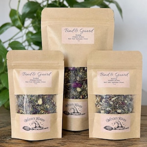 K&ouml;nnte beinhalten: Drei Kraftpapierbeutel mit Kr&auml;utermischung, beschriftet mit "Bind & Guard" und "Witch's Haven." Die Beutel enthalten getrocknete Kr&auml;uter und Blumen. Die Etiketten zeigen eine Illustration eines Hexenhuts und eines Besens.