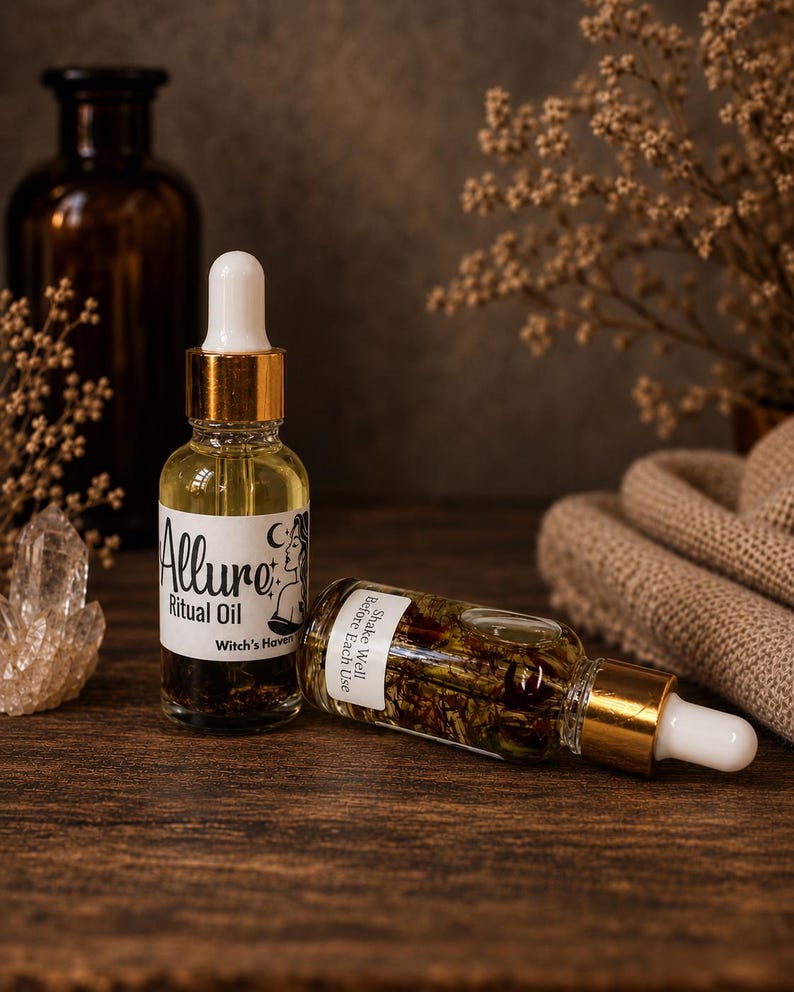 Puede incluir: Dos frascos cuentagotas de vidrio transparente con cuellos dorados y puntas blancas. Un frasco est&aacute; de pie con una etiqueta que dice Allure Ritual Oil Witch's Haven, mientras que el otro est&aacute; horizontal con la etiqueta Shake Well Before Each Use.