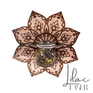 May include: A wooden, flower-shaped shelf with a decorative mandala design. A glass jar filled with dried flowers and herbs sits on a small shelf. The text "Lilac Laser" is written in cursive script.