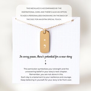 Puede incluir: Un collar con colgante rectangular dorado grabado con un punto y coma, presentado en una tarjeta blanca con el texto: In every pause, there's potential for a new story. La tarjeta incluye texto adicional sobre el significado del s&iacute;mbolo.