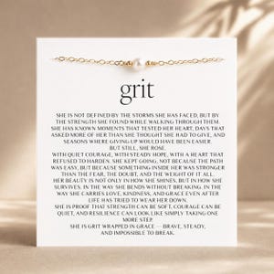 May include: A delicate gold chain bracelet featuring a single central white pearl, displayed on a white card printed with the word grit and a long inspirational paragraph about strength, resilience, and grace in black serif font.