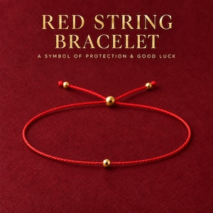 Könnte beinhalten: Ein rotes Schnurarmband mit einer einzelnen goldfarbenen Perle in der Mitte und einem verstellbaren Verschluss mit drei weiteren goldfarbenen Perlen. Der Text RED STRING BRACELET A SYMBOL OF PROTECTION & GOOD LUCK steht über dem Schmuckstück.