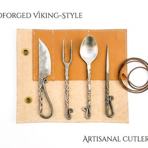 May include: Hand-forged Viking-style artisanal cutlery set. The set includes a knife, fork, spoon, and a pointed utensil, all with twisted handles and a leather carrying case. The text "Handforged Viking-Style" and "Artisanal Cutlery Set" are visible.