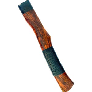 May include: A wooden axe handle with a dark brown finish and a black grip. The handle has a natural wood grain pattern and a black cap on the top. The grip is wrapped with black leather.