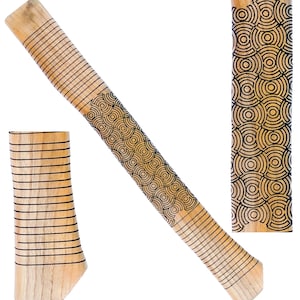 May include: A light-colored wooden handle with a geometric pattern of black circles and lines. The handle is angled, with a separate piece of wood at the base. The design is repeated on a smaller, vertical piece.