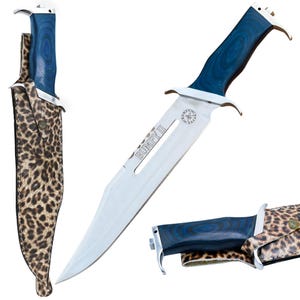May include: A large stainless steel knife with a blue wooden handle and a leopard print sheath. The blade is engraved with "BUMPY II". The knife has a silver guard and a pointed tip. The sheath is brown and tan.