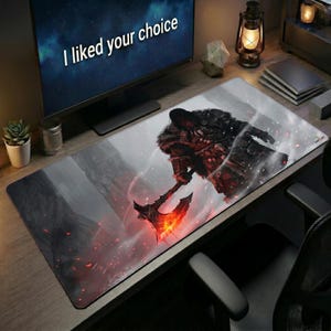 May include: A rectangular desk mat featuring a dark, atmospheric illustration of a warrior in fur-lined armor wielding a glowing, fiery axe. The design includes swirling smoke, embers, and a rocky landscape in shades of gray, black, and vibrant orange.