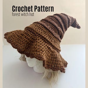 Könnte beinhalten: Ein brauner Häkel-Hexenhut mit breiter, gewellter Krempe und spitzer Krone. Der Hut wird auf einem Schaufensterkopf präsentiert. Der Text "Crochet Pattern forest witch hat" befindet sich oben im Bild.