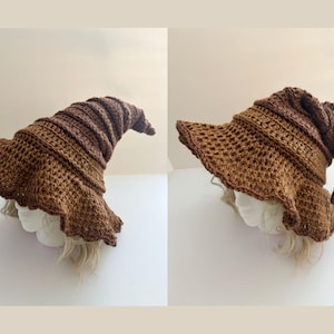 May include: A brown crochet witch hat with a wide, ruffled brim and a pointed, curled top. The hat is made of a textured yarn, and the color is a warm, earthy brown. The hat is displayed on a mannequin head.