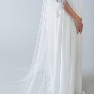 Puede incluir: Un velo de novia blanco con delicados detalles de encaje en los bordes. El velo est&aacute; hecho de una tela suave y transparente y tiene un dise&ntilde;o fluido y elegante.