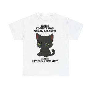 Könnte beinhalten: Weißes T-Shirt mit einer Cartoon-Katze mit grünen Augen. Der Text auf dem Shirt lautet "HANS KÖNNTE DAS SCHON MACHEN" und "HANS HAT NUR KEINE LUST".