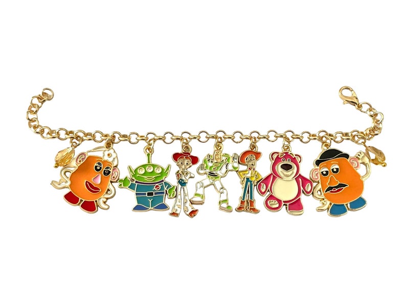 May include: Gold-toned charm bracelet featuring colorful enamel charms of characters from the animated film series. The charms include Mr. Potato Head, an alien, Jessie, Buzz Lightyear, Woody, Lotso, and another Mr. Potato Head.