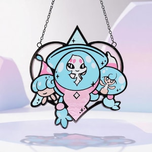 Puede incluir: Una vidriera con un diseño de dibujos animados de tres figuras en azul, rosa y blanco, delineadas en negro. La ventana está suspendida por una cadena y tiene un marco en forma de corazón. Diseño caprichoso.
