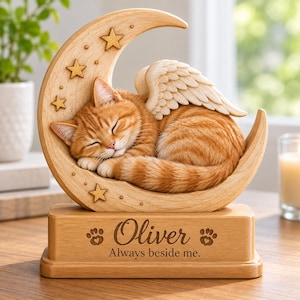 May include: A light wood-toned figurine featuring a sleeping orange tabby cat with feathered wings resting on a crescent moon decorated with stars. The rectangular base is engraved with the name Oliver, two paw prints, and the text Always beside me.