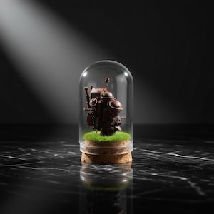 May include: A miniature, steampunk-style machine, in shades of brown and copper, is encased in a glass dome. The base features a cork ring and a patch of green artificial grass. The background is dark, with a spotlight illuminating the display.