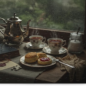 Könnte beinhalten: Ein gemütliches Stillleben mit einer silbernen Teekanne, zwei Teetassen und Scones mit Marmelade auf einem Teller. Ein Buch, eine Brille und ein Zuckertopf sind ebenfalls vorhanden. Die Szene spielt sich an einem regnerischen Fenster ab.