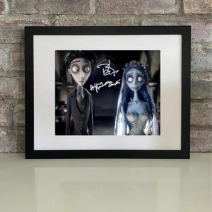 May include: A framed print featuring characters from the animated film, "Corpse Bride." The image shows a man in a black suit and a woman in a wedding dress. The print is in a black frame and has a white mat.
