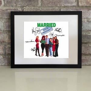 May include: Framed print featuring the cast of "Married... with Children" with signatures. The title "Married with Children" is in green text. The cast is standing together, with the women in dresses and the men in casual attire. The frame is black.