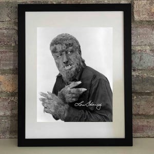 Op de afbeelding: Zwart-wit ingelijste print met Lon Chaney als de Wolfman. De afbeelding toont Chaney in karakter, met een harig gezicht en handen, gekleed in een donker overhemd. De handtekening "Lon Chaney" is rechtsonder zichtbaar.