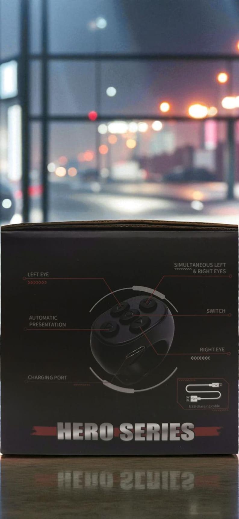 Puede incluir: Caja negra con el texto "HERO SERIES" y diagramas de un dispositivo con botones, etiquetados como "LEFT EYE", "RIGHT EYE", "SWITCH" y "CHARGING PORT". Tambi&eacute;n se muestra un cable de carga USB.