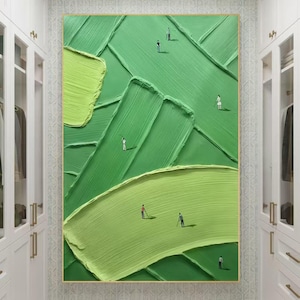 May include: Abstract green golf course painting with textured brushstrokes. The artwork features miniature figures of golfers on the course. The painting is framed in a gold-coloured frame and hangs in a white wardrobe.
