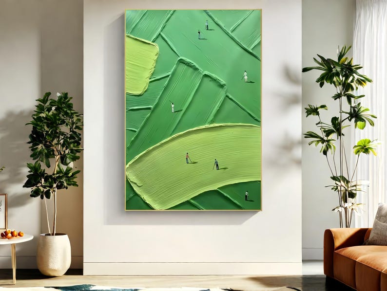 May include: Abstract green textured painting in a gold frame. The artwork features various shades of green with small figures scattered across the surface, creating a sense of depth and scale. The painting is displayed on a white wall.