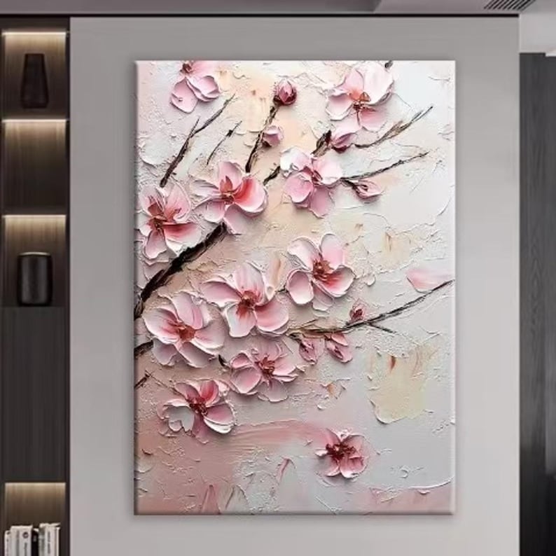 May include: A textured canvas art piece featuring a blossoming cherry tree branch. The artwork showcases raised pink flowers with dark brown branches against a white and light pink background. The painting evokes a sense of spring and nature.