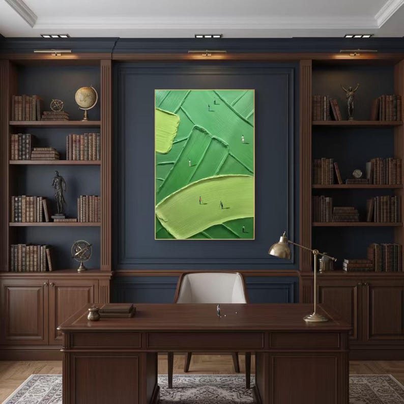 May include: Abstract green painting with textured brushstrokes in a gold frame. The artwork features varying shades of green, creating a sense of depth and movement. The painting is displayed in a room with a dark blue wall, wooden bookshelves, and a desk.