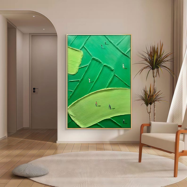 May include: Abstract green golf course painting with a gold frame. The artwork features textured brushstrokes and tiny figures of golfers. The painting is displayed in a modern interior setting with a neutral color palette.