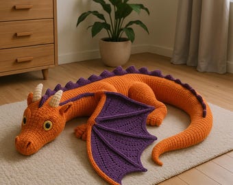 May include: A large, orange and purple crocheted dragon toy with yellow eyes, white horns, and purple wings. The dragon is lying on a light-colored rug. The dragon's body is orange with purple spines.