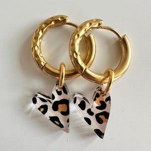 Könnte beinhalten: Ein Set aus drei Keramikbechern mit gesprenkelter, matter Oberfläche. Die Becher sind in Creme-, Hellgrau- und Dunkelgrautönen gehalten. Jeder Becher hat ein schlichtes, minimalistisches Design.