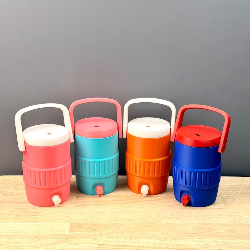 May include: Four colorful water coolers with white, pink, orange, and blue bodies. Each cooler has a matching lid and handle, and a white spigot. The coolers are arranged in a row against a gray background.