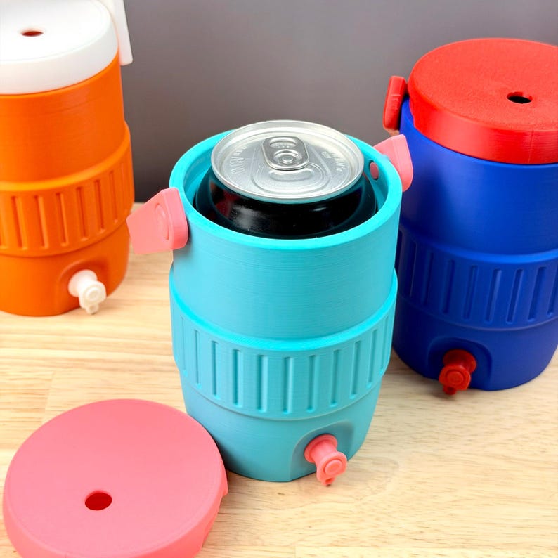 May include: A collection of colorful, cylindrical beverage coolers in blue, orange, and red. The coolers have a tap at the bottom and a lid on top. One cooler holds a can of soda. The coolers are designed to keep drinks cold.