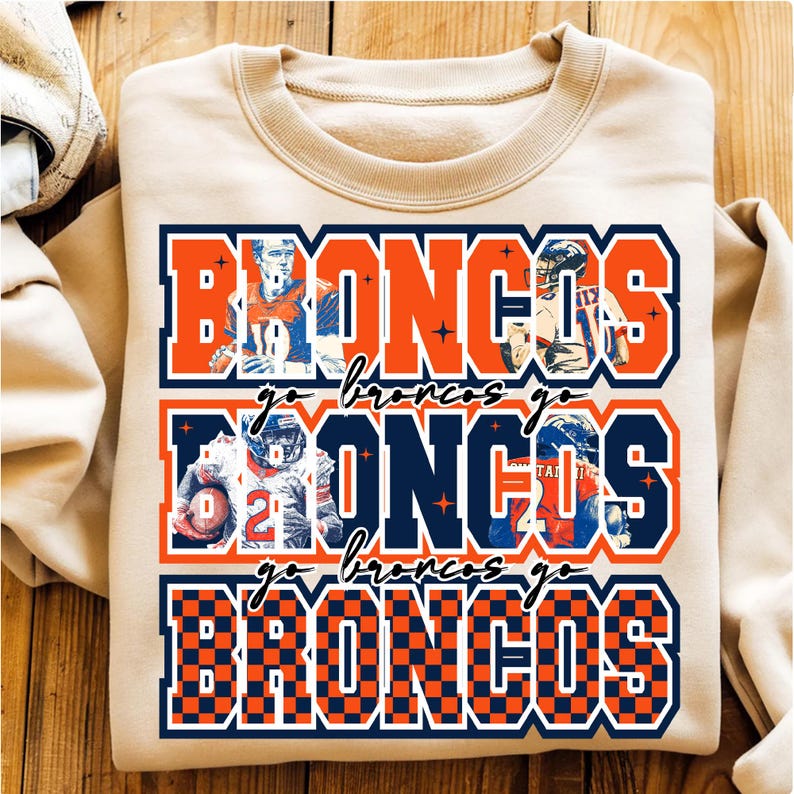May include: A beige sweatshirt with the word "BRONCOS" in orange and navy blue block letters. The word "BRONCOS" is repeated three times with images of football players. The words "go broncos go" are written in cursive.