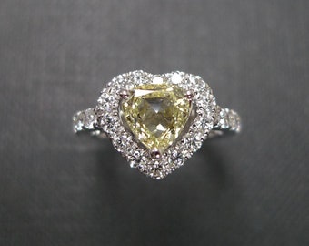 Könnte beinhalten: Ein herzförmiger Verlobungsring mit einem gelben Mittelstück, das von einem Heiligenschein aus kleineren Diamanten umgeben ist.