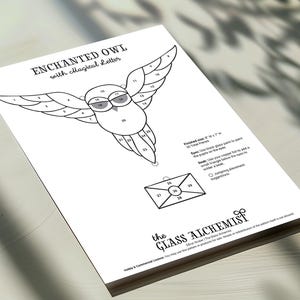 May include: A white paper featuring a black line drawing of an owl with outstretched wings and an envelope. The text "ENCHANTED OWL with magical Letter" is at the top. The finished size is 20 cm W x 18 cm H. The Glass Alchemist logo is at the bottom.