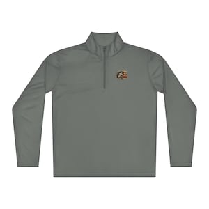 May include: A grey long-sleeved pullover with a quarter-zip neckline. The shirt has a small emblem on the upper left chest with a cross, an eagle, and an American flag design. The shirt is made of a smooth, lightweight material.