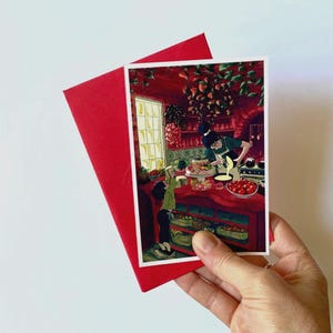 May include: A red envelope and a greeting card featuring a kitchen scene with two people. The card shows a person preparing food with another person looking on. The kitchen is decorated in red tones, with a window and shelves.