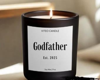 May include: A matte black glass candle jar with a white label featuring the text VITEO CANDLE, Godfather, Est. 2025, and Soy Wax | 9 oz. The candle has a lit wick and is accompanied by a black graphic element with the text GIFT BOX INCLUDED.