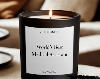 May include: A matte black candle in a glass jar with a white label that reads VITEO CANDLE, World’s Best Medical Assistant, and Soy Wax | 9 oz. A lit wick is visible at the top. A black graphic in the corner states GIFT BOX INCLUDED.
