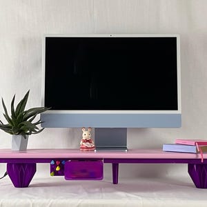 May include: A pink and purple desk organizer with a computer monitor on top. The desk has a drawer, a small plant, and a decorative figurine. The desk is approximately 30 inches wide.